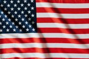 A close-up of a folded, textured American flag featuring red and white stripes and a blue canton with white stars.
