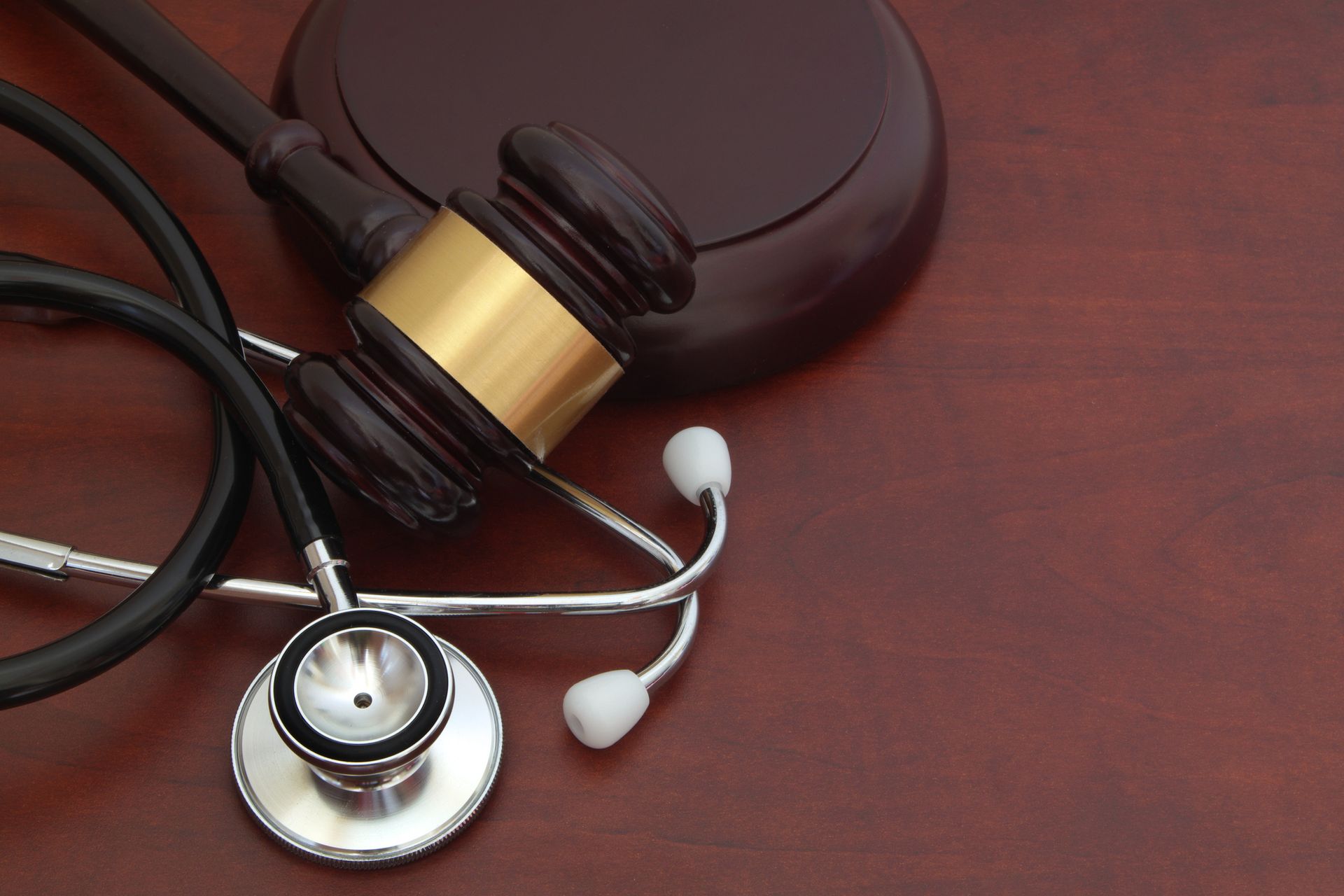 Gavel and stethoscope on a wood surface, symbolizing healthcare law. Gavel and stethoscope on a wood surface, symbolizing healthcare law.