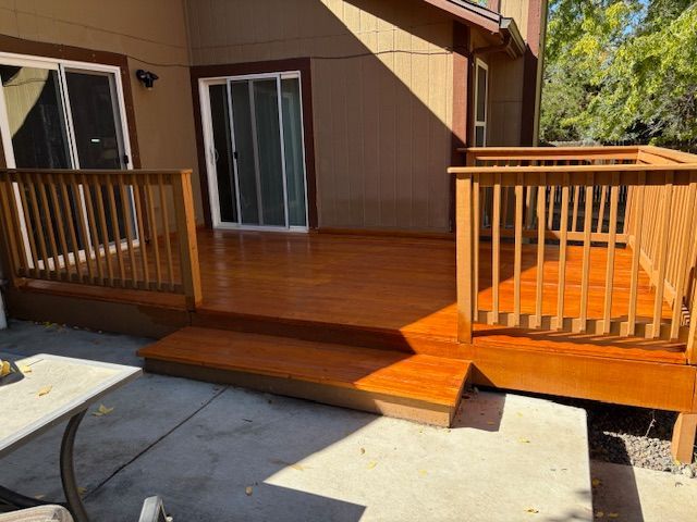 Wooden deck with railing, steps, and sliding glass door. The deck is stained brown.