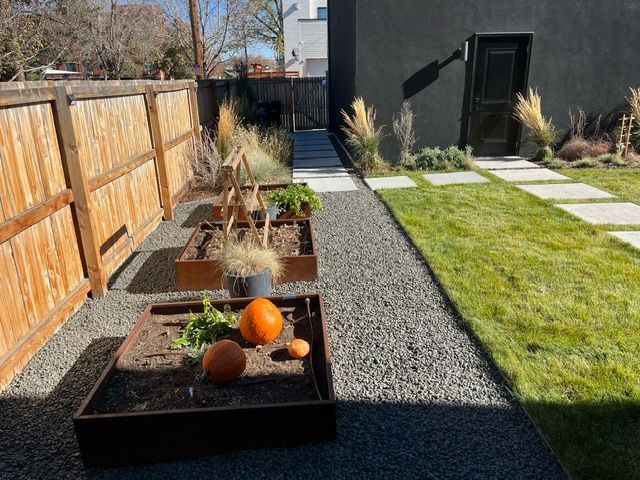 A backyard with a fence and a planter with pumpkins in it