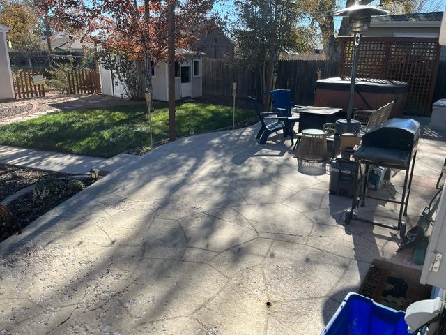 A patio with a table and chairs and a hot tub in the backyard.