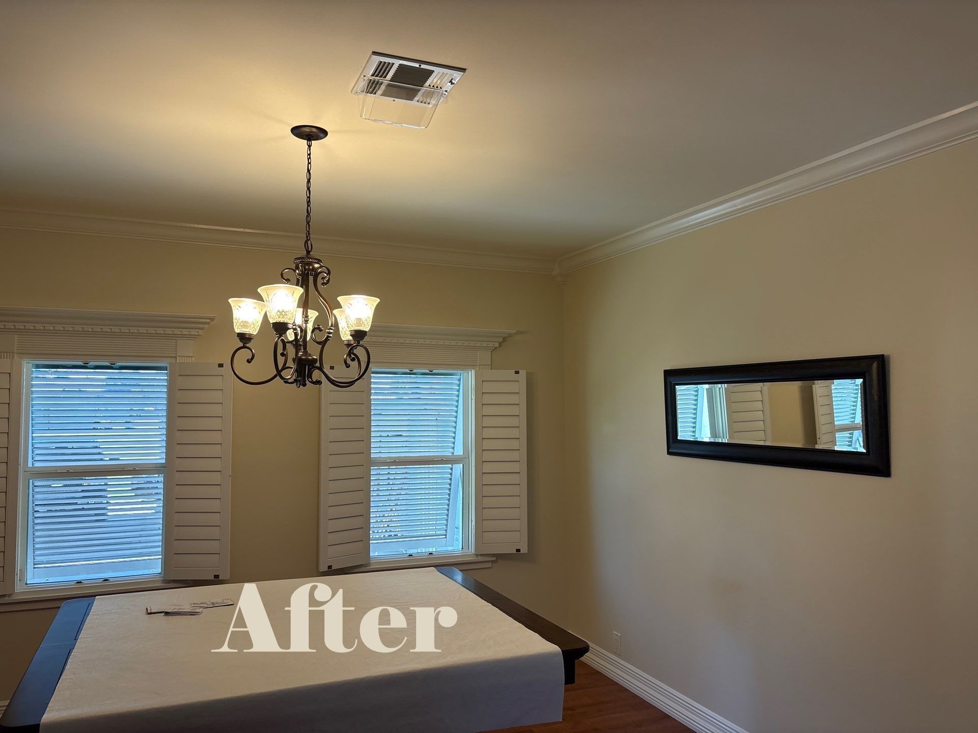 Dining room with chandelier, windows, mirror, and beige walls.