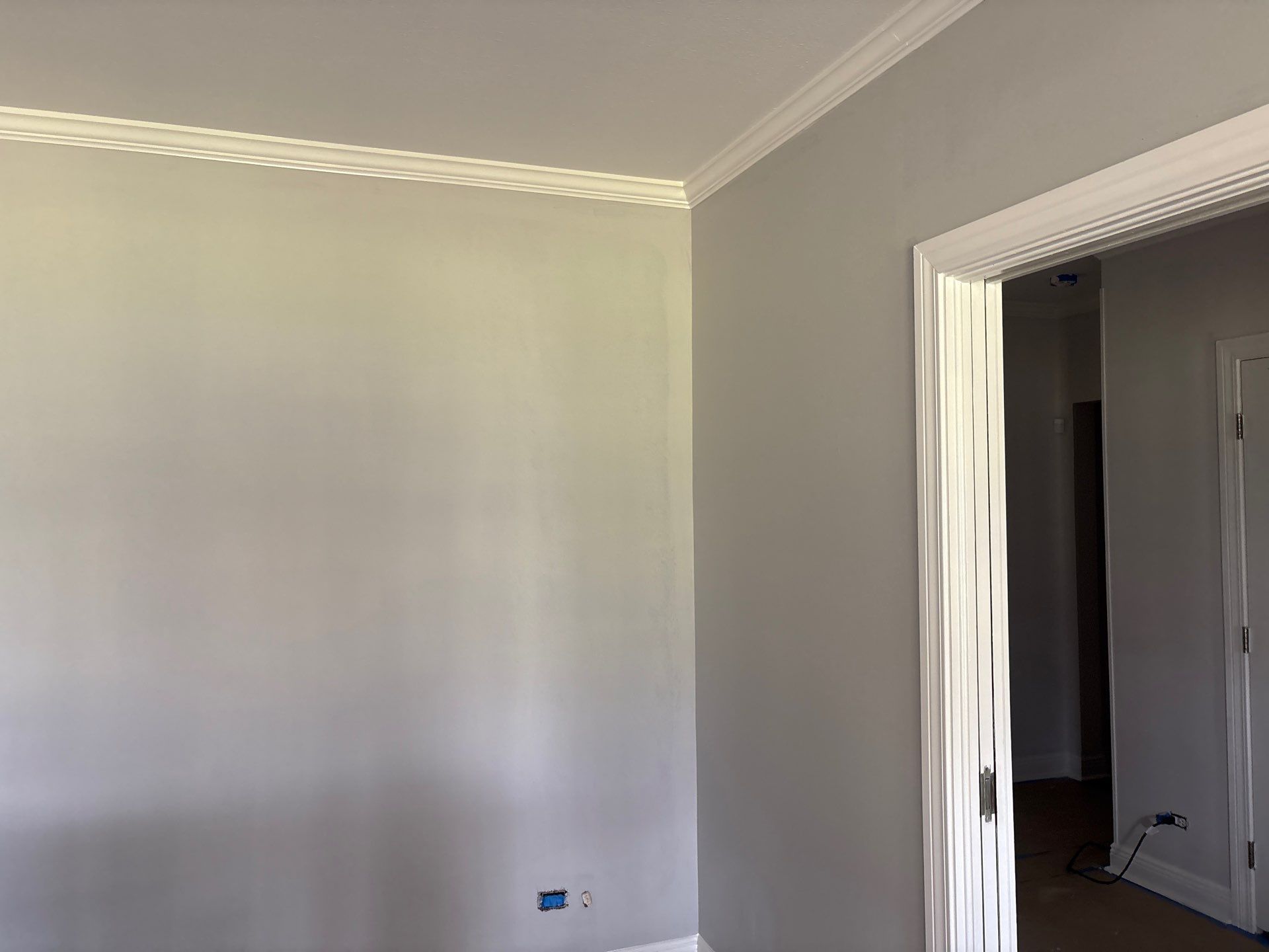 Gray painted room corner with white crown molding. Doorway on the right.
