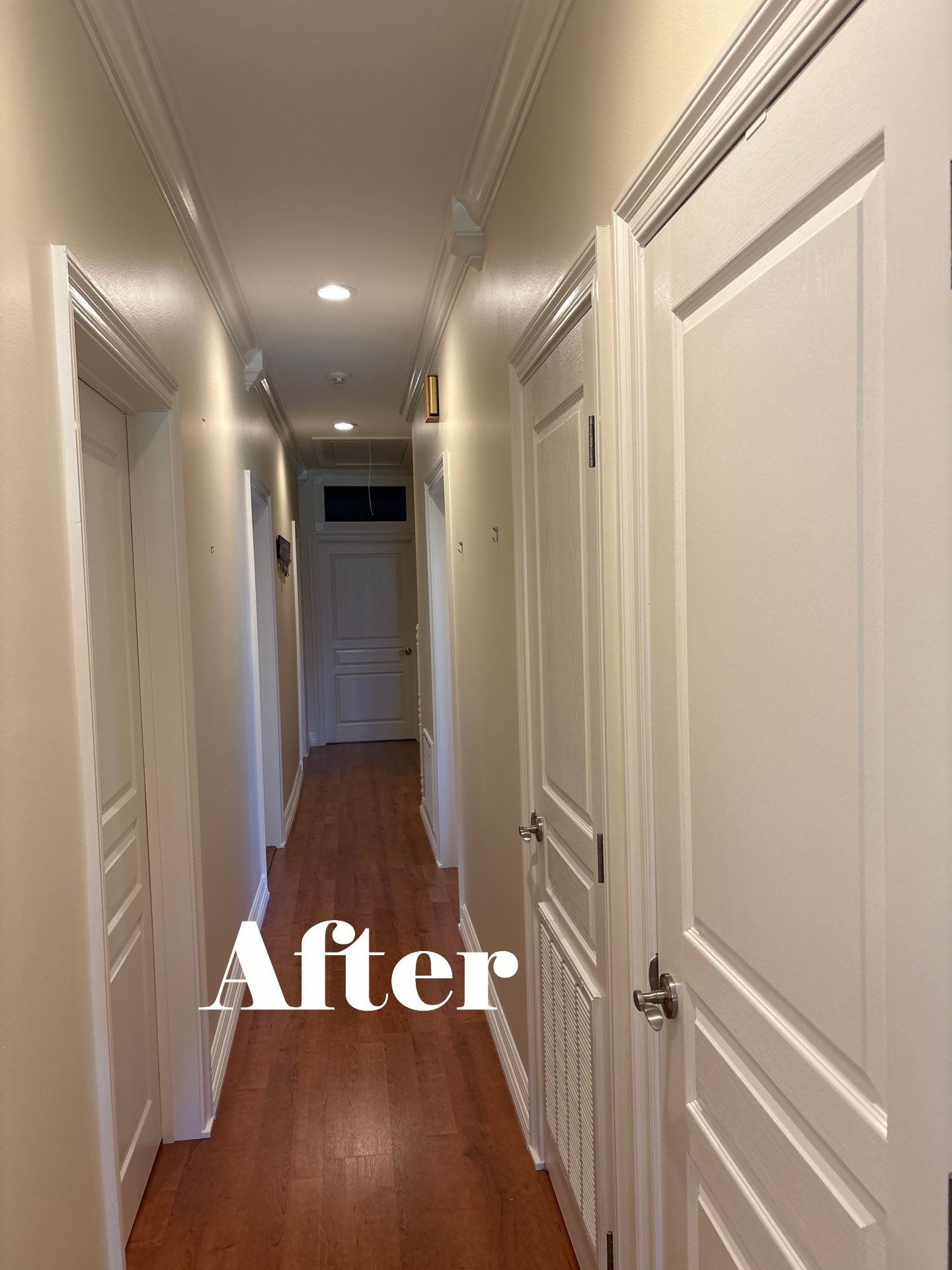 Hallway with beige walls, white doors, and hardwood floors.