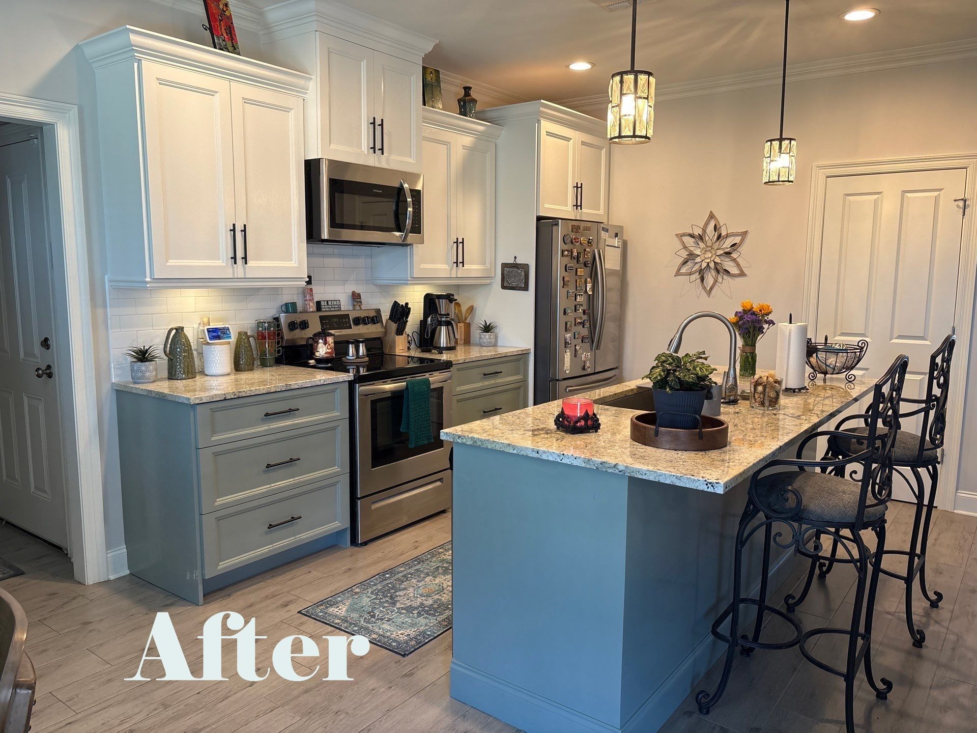 Newly renovated kitchen with white and blue cabinets, stainless steel appliances, and a central island with bar stools.