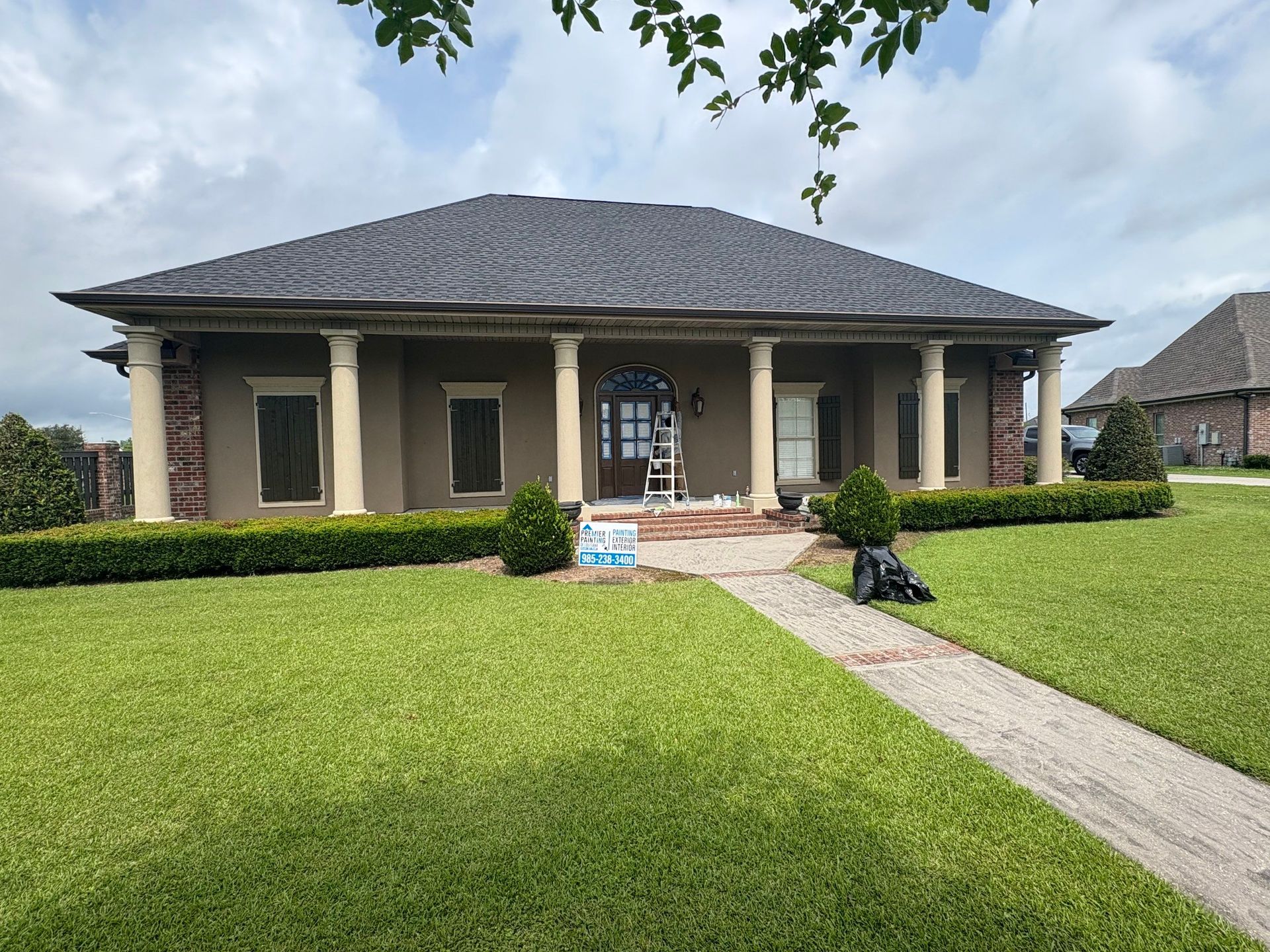 A large house with a gray roof is sitting on top of a lush green lawn.