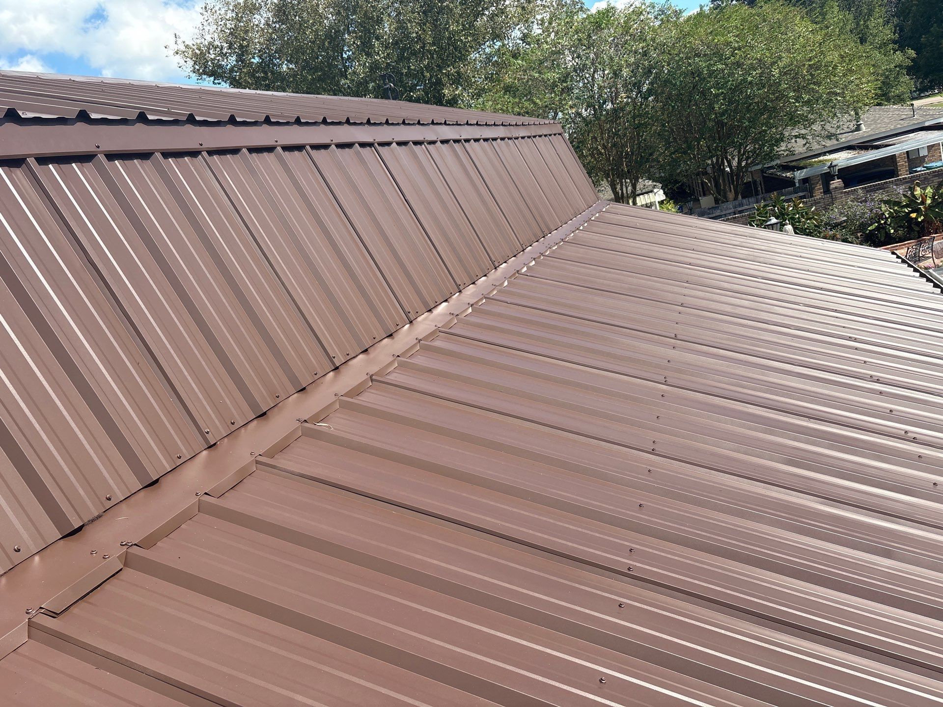 Brown metal roof with vertical ridges on a building, angled view.