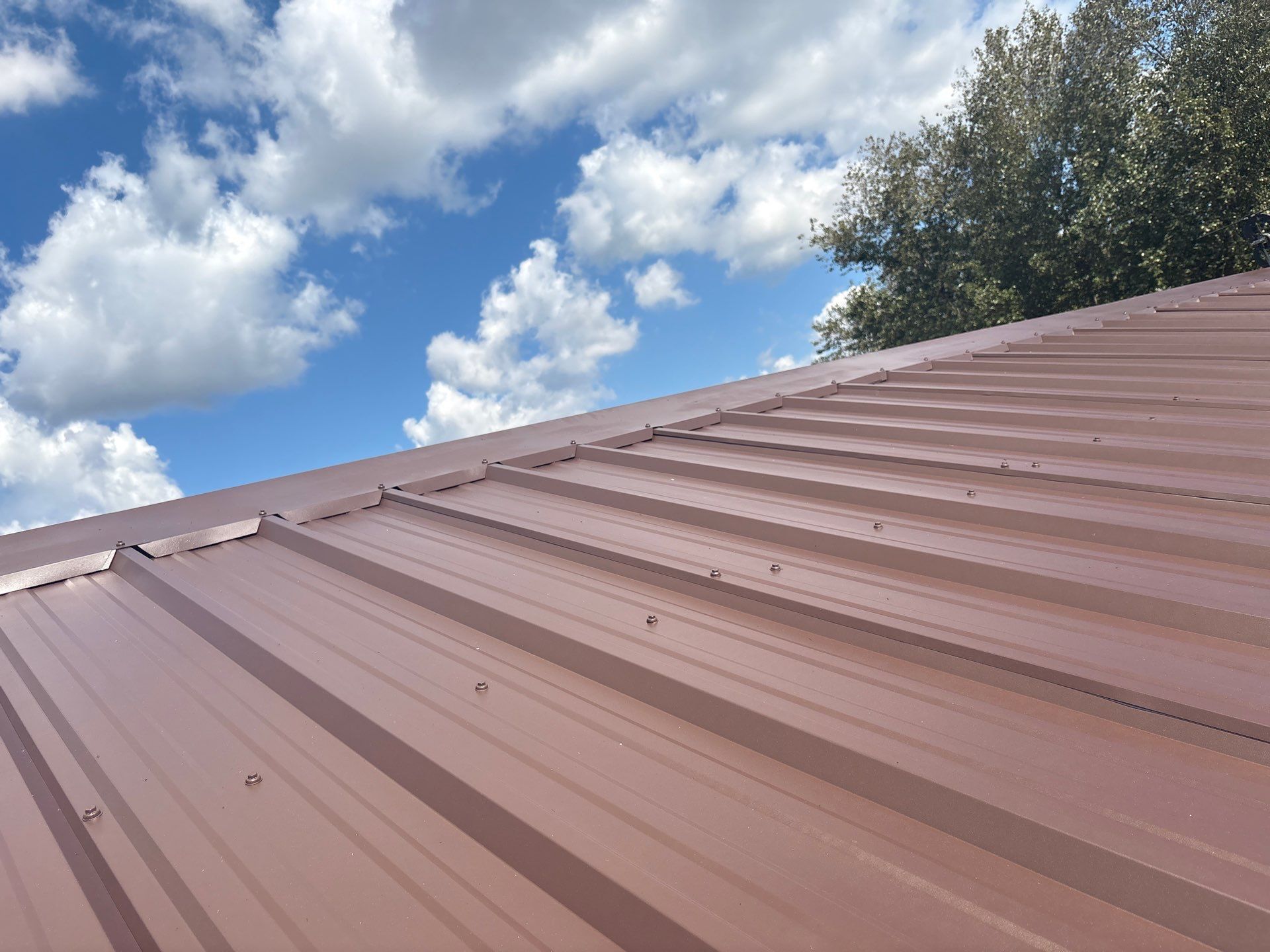 Brown metal roof against a partly cloudy blue sky.