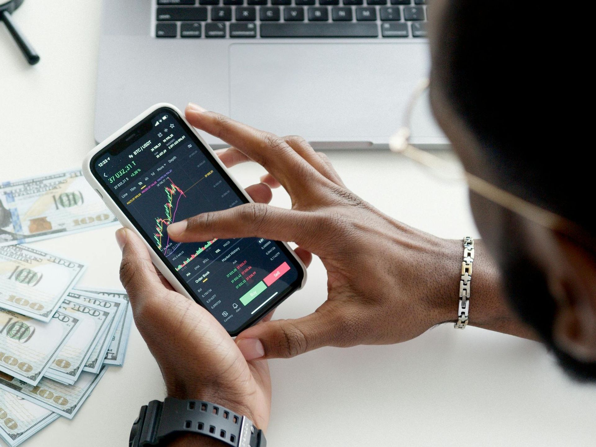 A man is holding a cell phone with a graph on it.