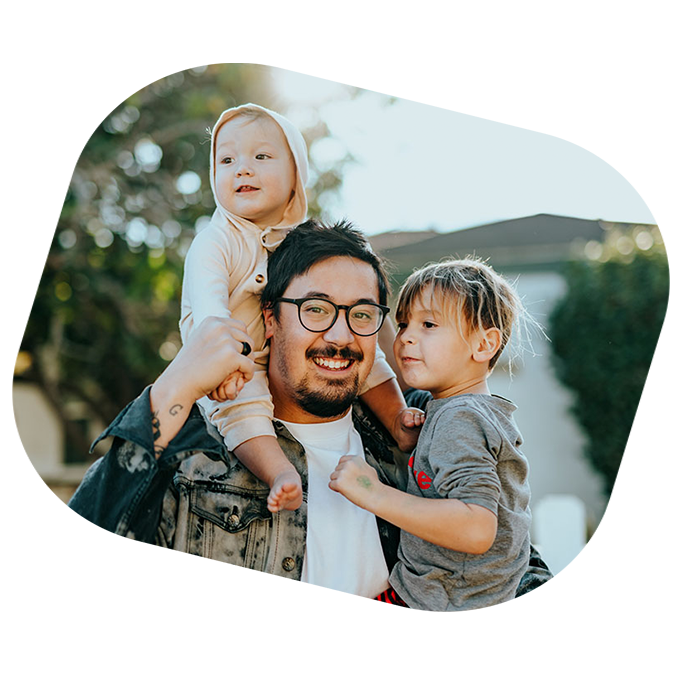 father with baby on his shoulders and holding young boy