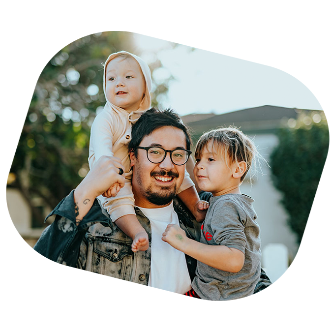 father with baby on his shoulders and holding young boy