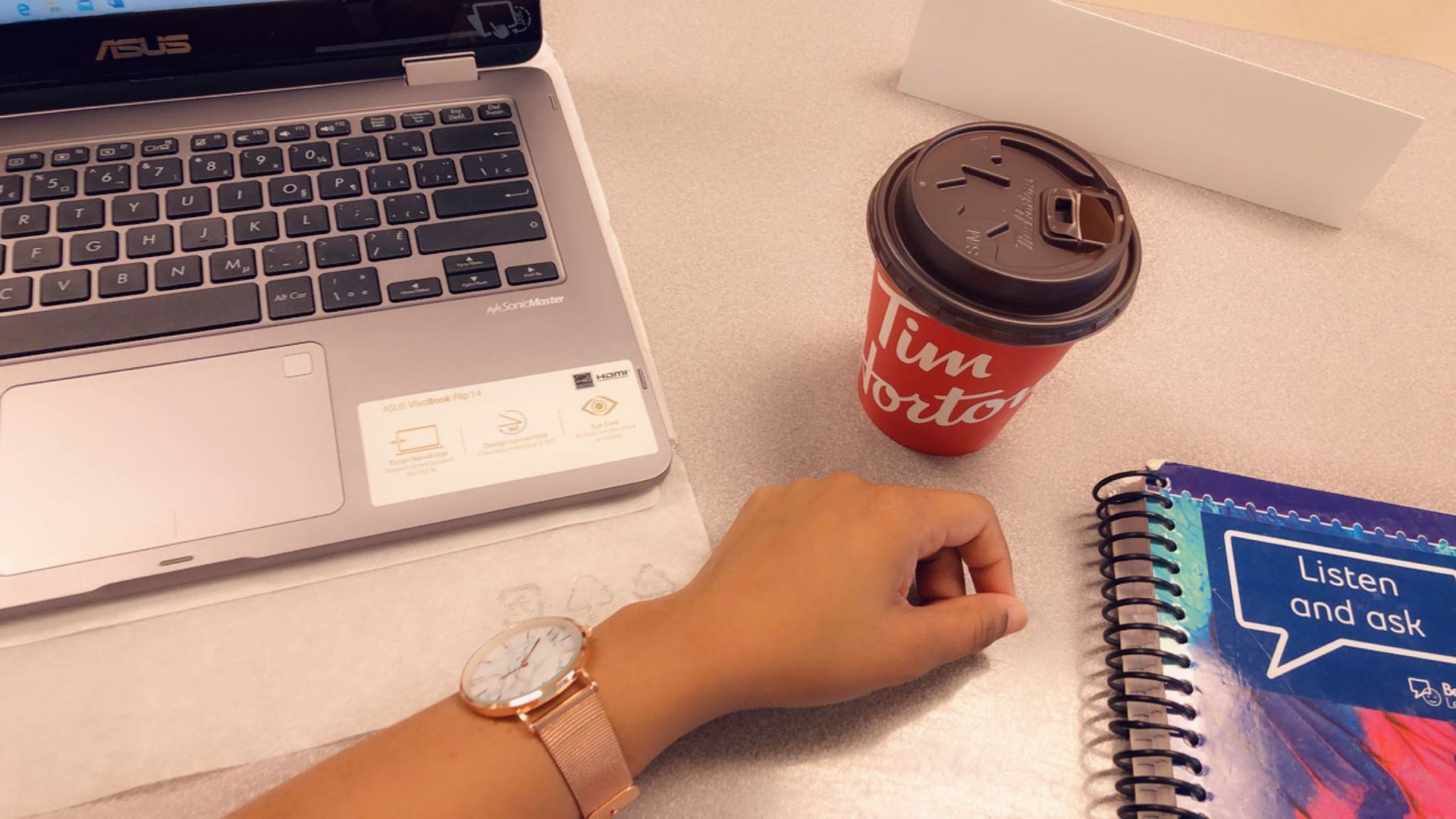 The author's hand rested on her school desk, with a coffee cup, laptop and notebook scattered around.