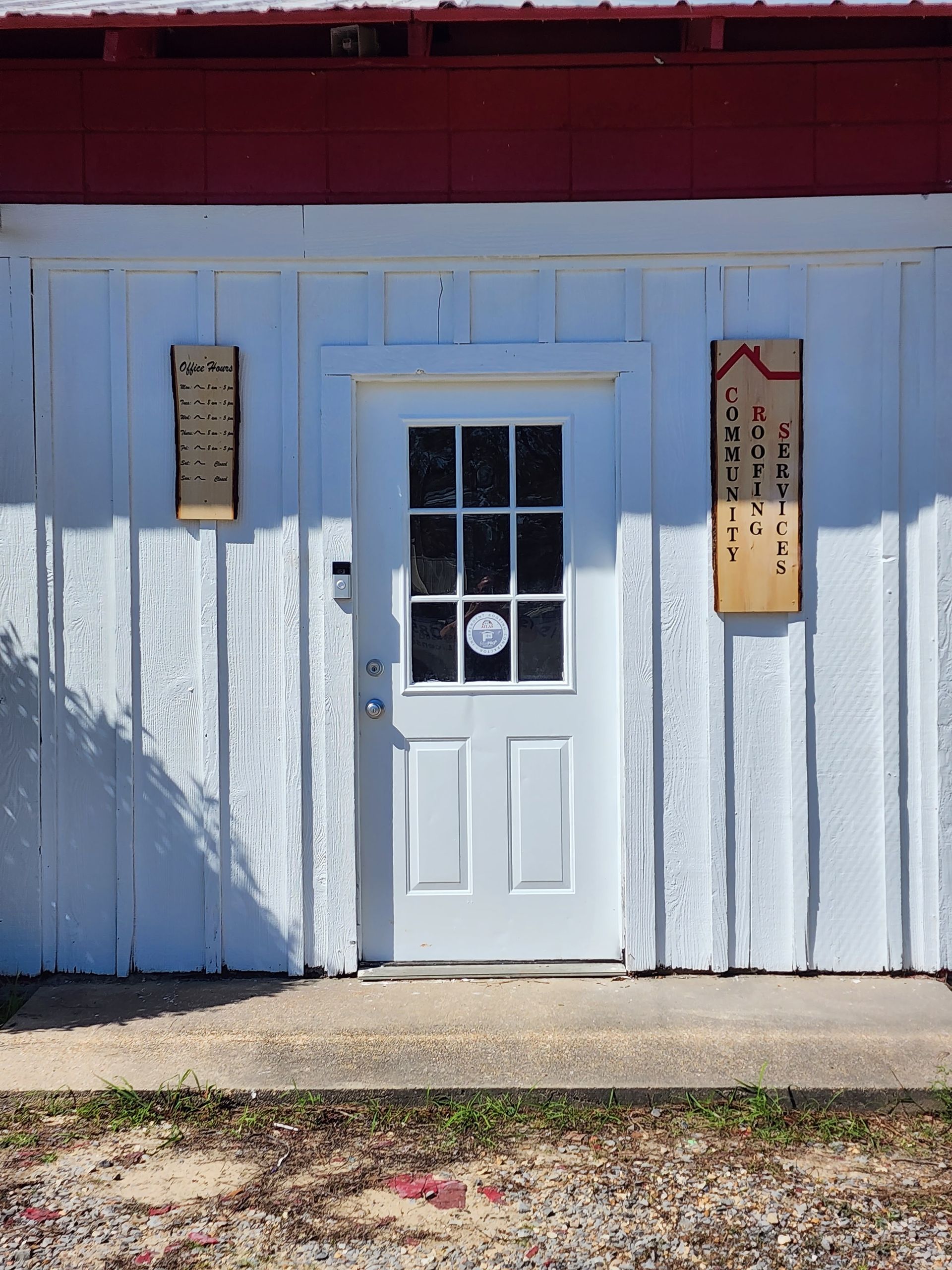 White door on a blue wooden storefront with red trim and hanging signs