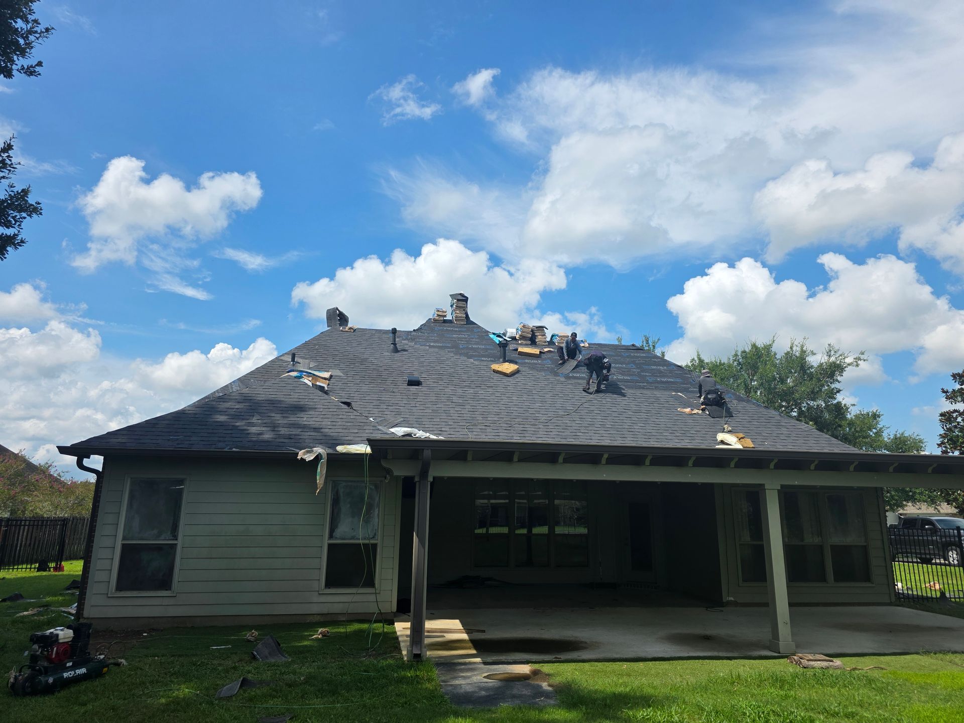 House with roof damage under a blue sky with clouds