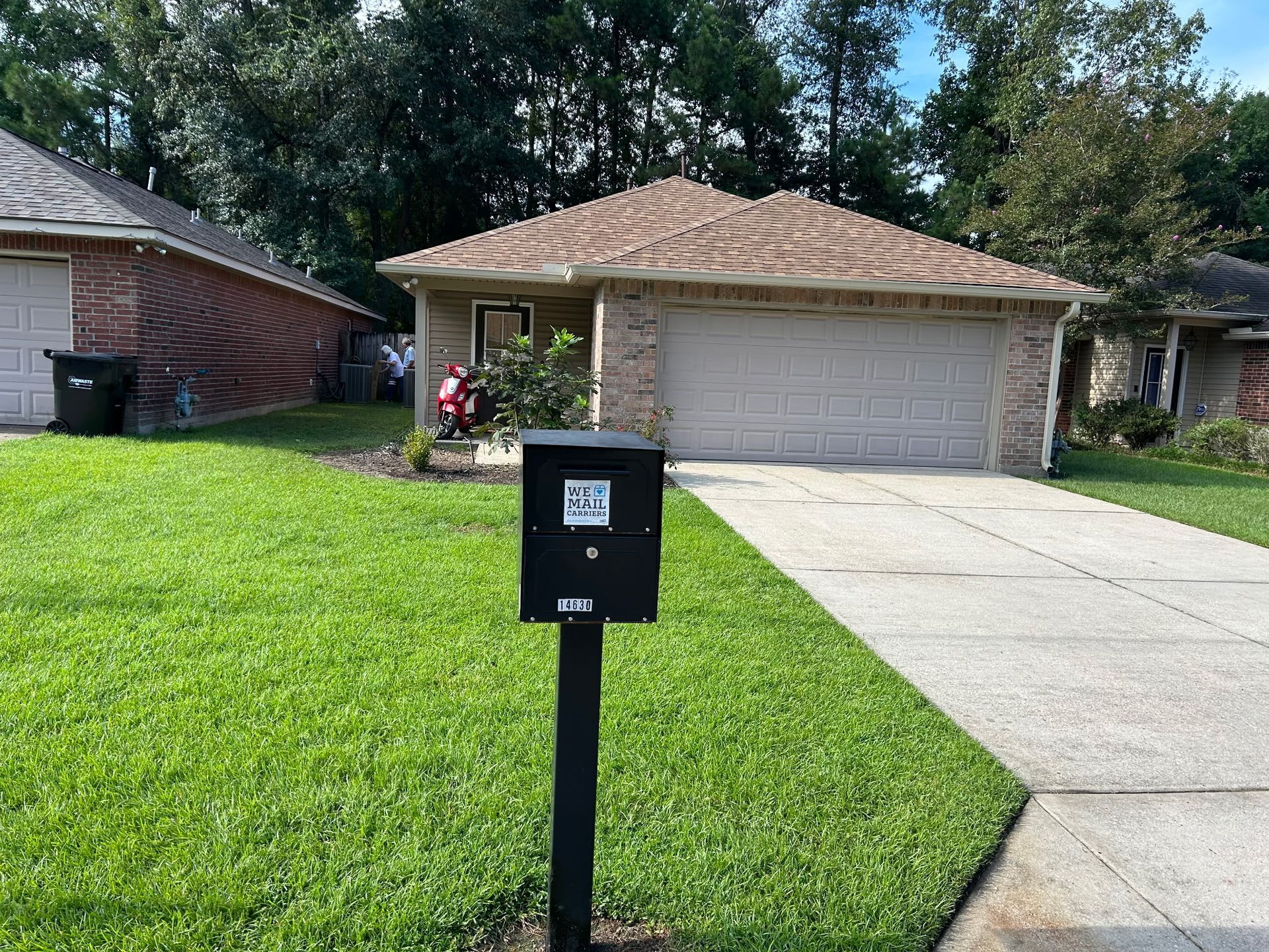 Mailbox in front of a suburban house with a driveway and green lawn.