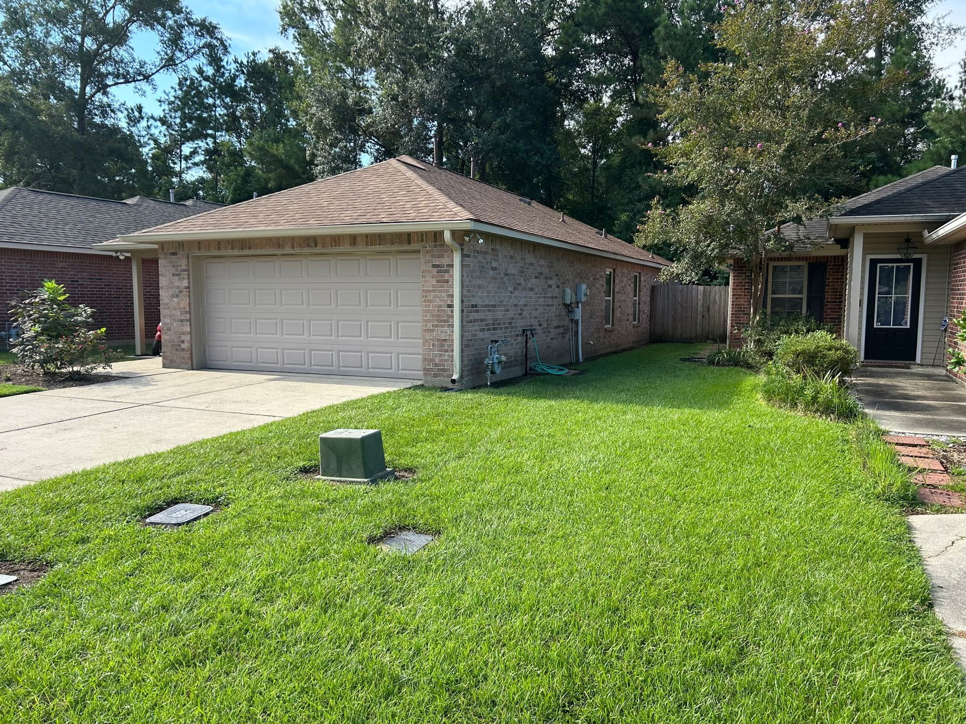 Suburban front yard with bright green lawn, two-car garage, and a walkway beside the house