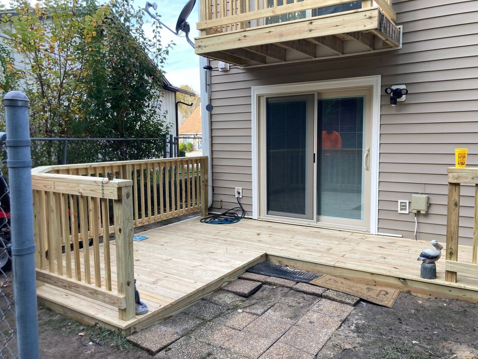 Back patio with wooden railing, sliding glass door, and a damaged section of deck boards