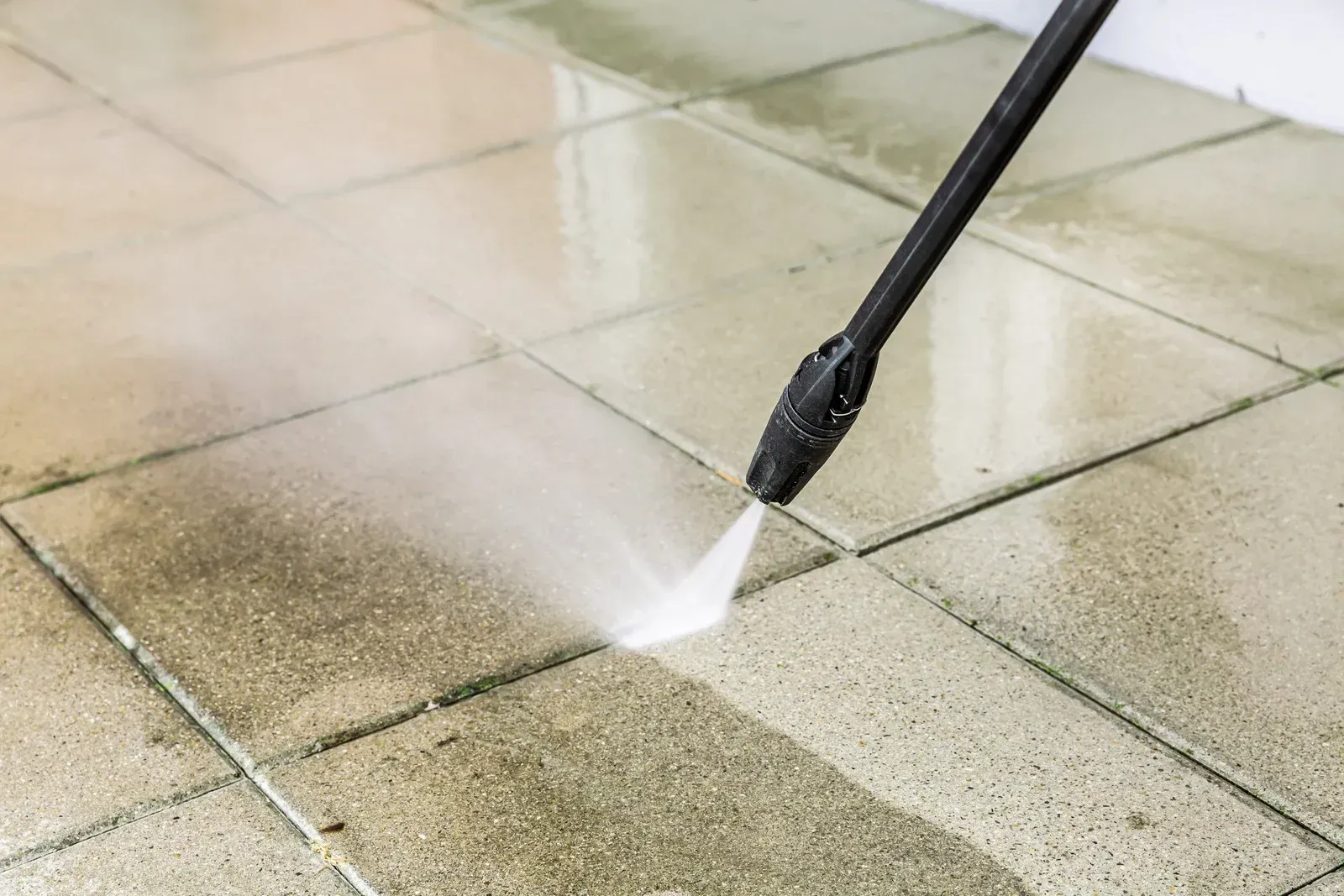 Pressure washer cleaning tiled pavement with a spray of water