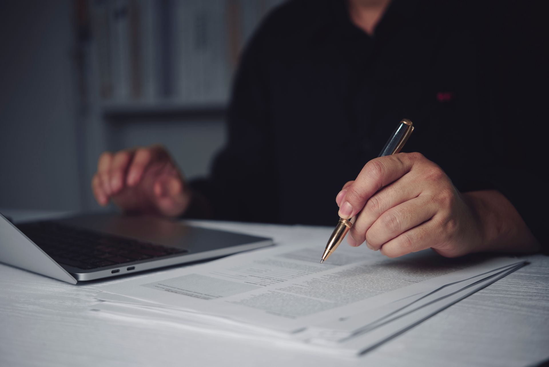 Businessman hand holding pen reviewing document.