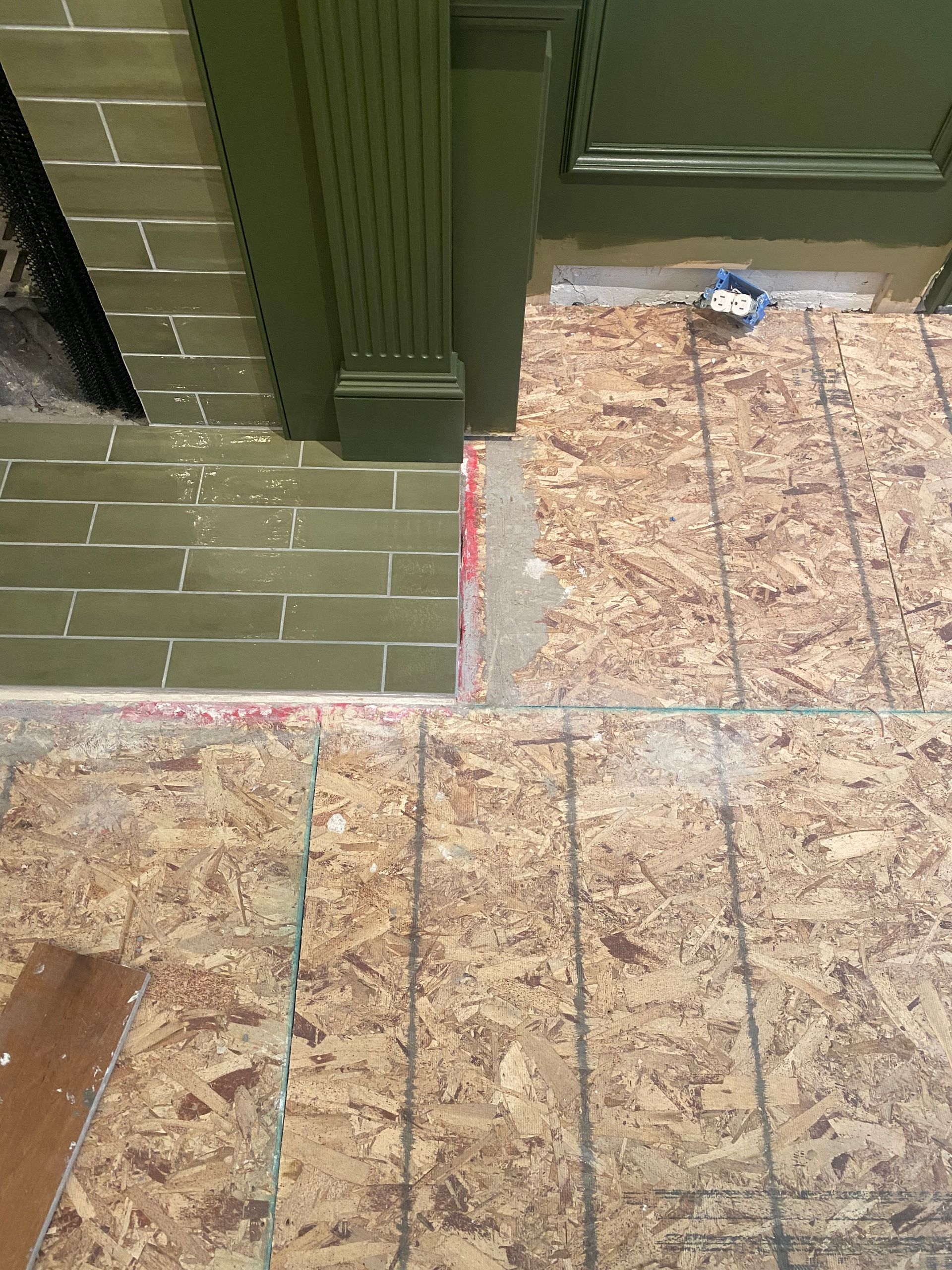 A wooden floor with a green door in the background.