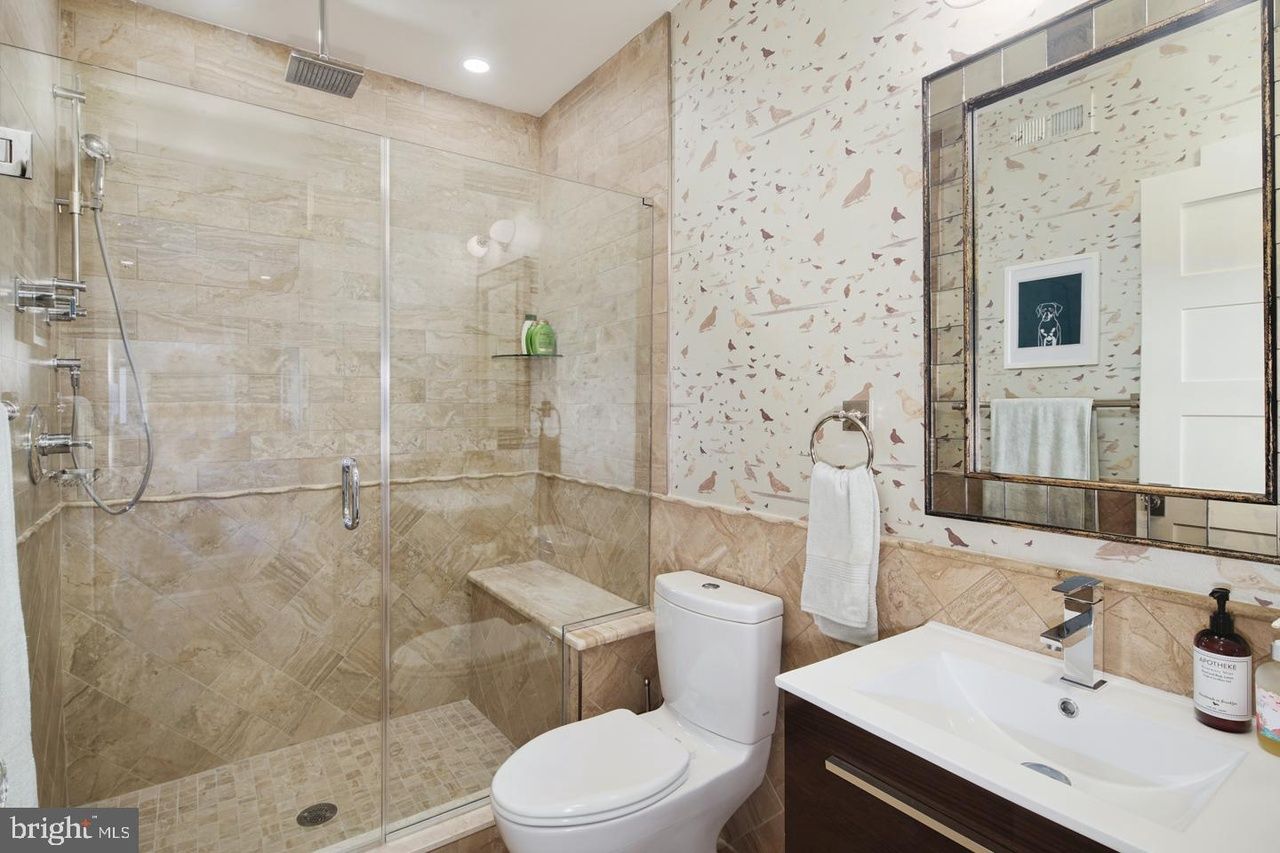 A bathroom with a toilet , sink , shower and mirror.