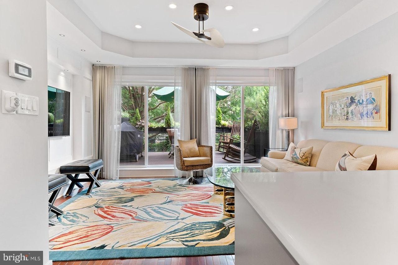 A living room with a couch , chair , rug and ceiling fan.