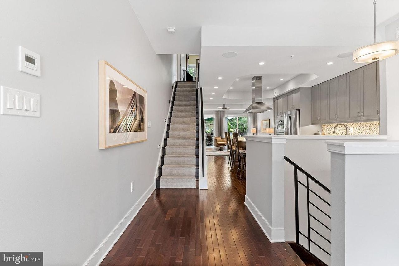 A hallway in a house with hardwood floors and stairs leading up to the second floor.