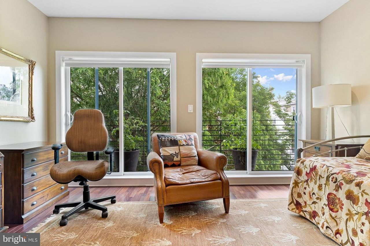 A bedroom with a bed , chair , desk and sliding glass doors.