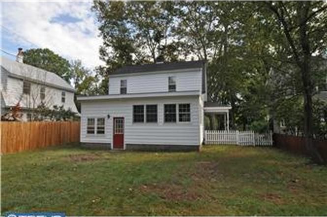 A white house with a red door is for sale