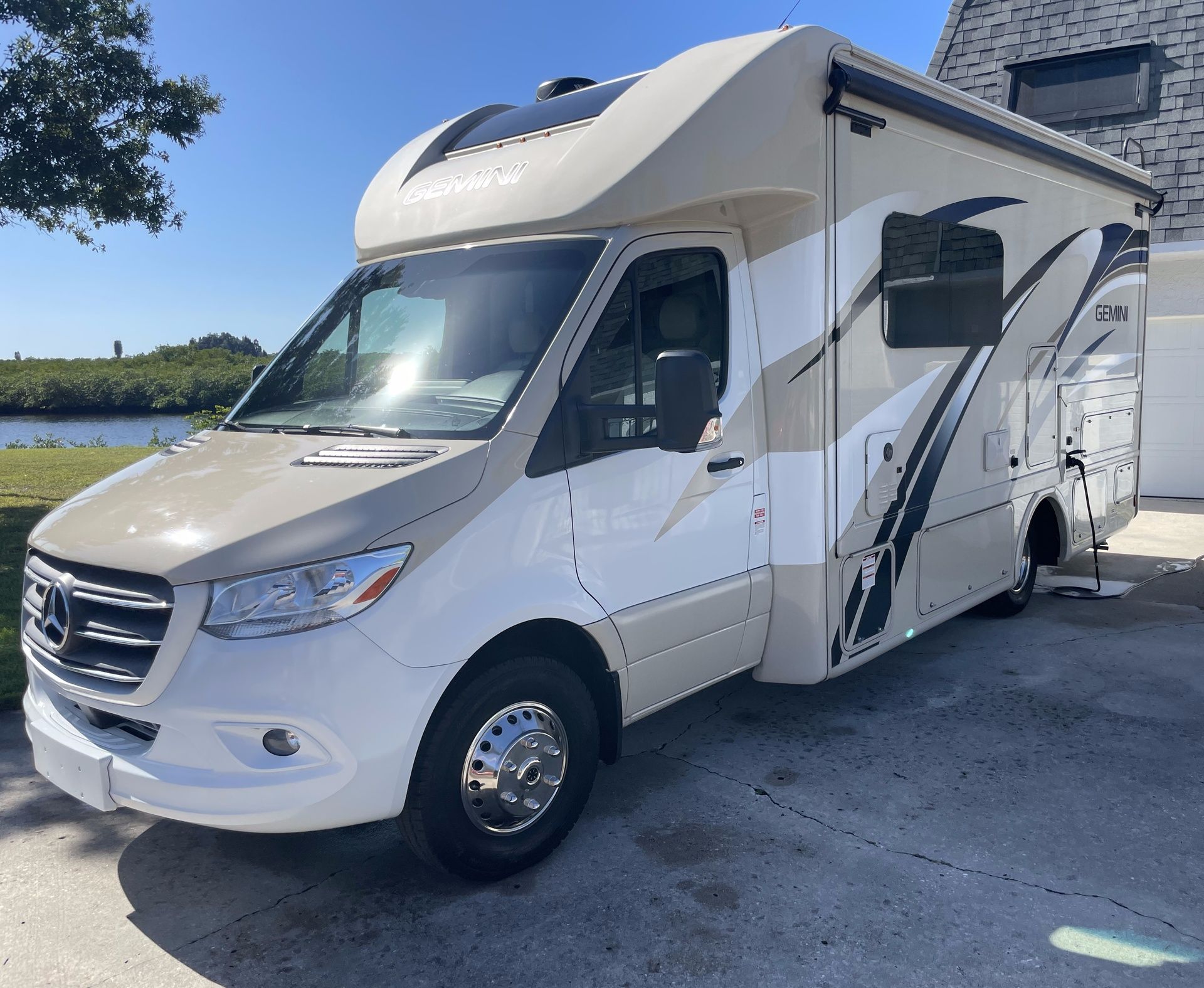 a rv is parked in a driveway next to a house .