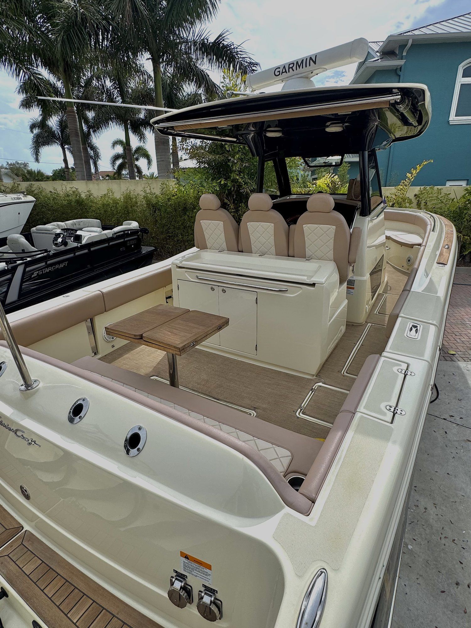 Boat helm with wooden steering wheel on a white motorboat cruising on blue water under a clear sky
