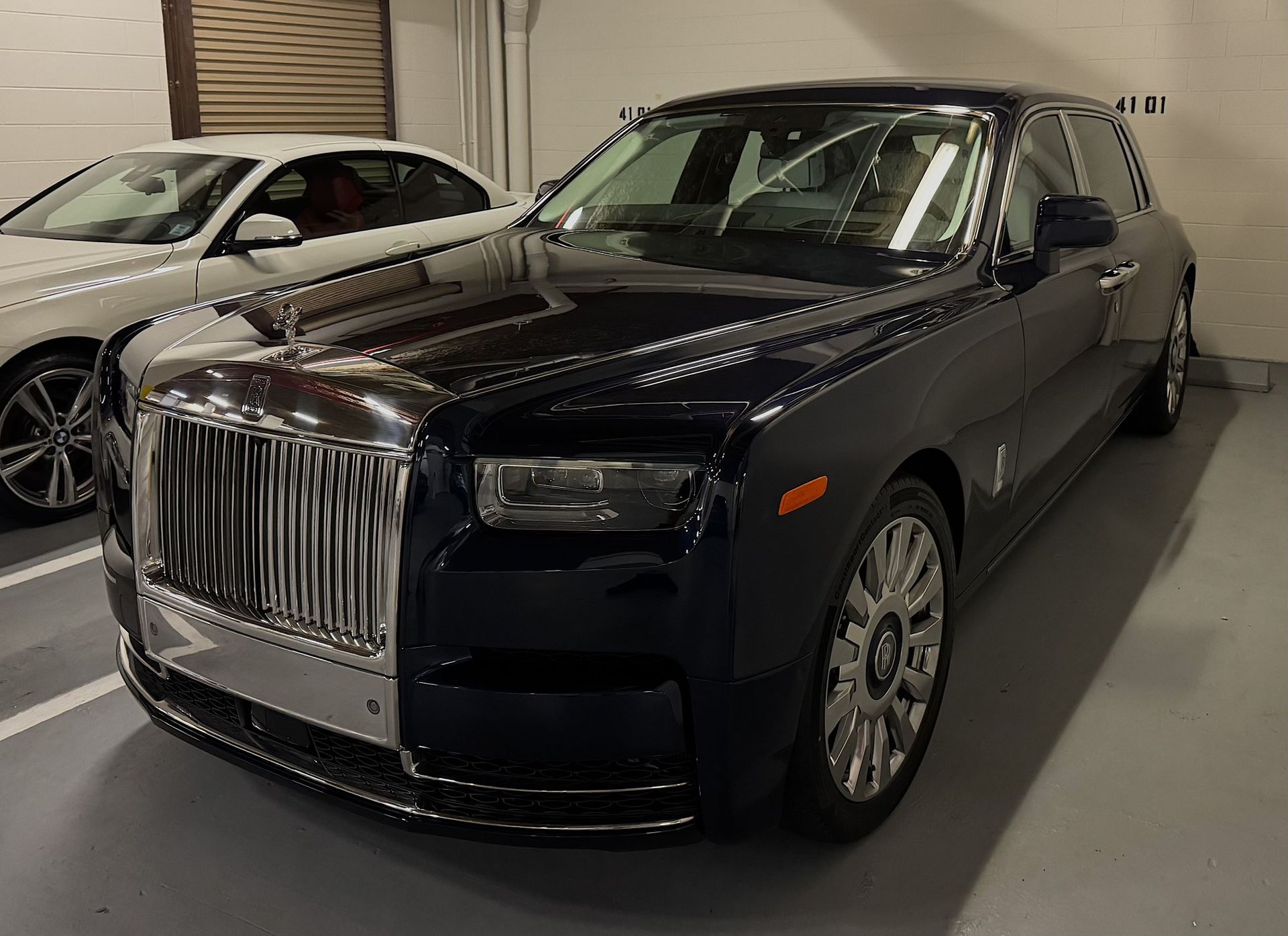 Black Rolls-Royce sedan parked indoors, front view with chrome grille and headlights