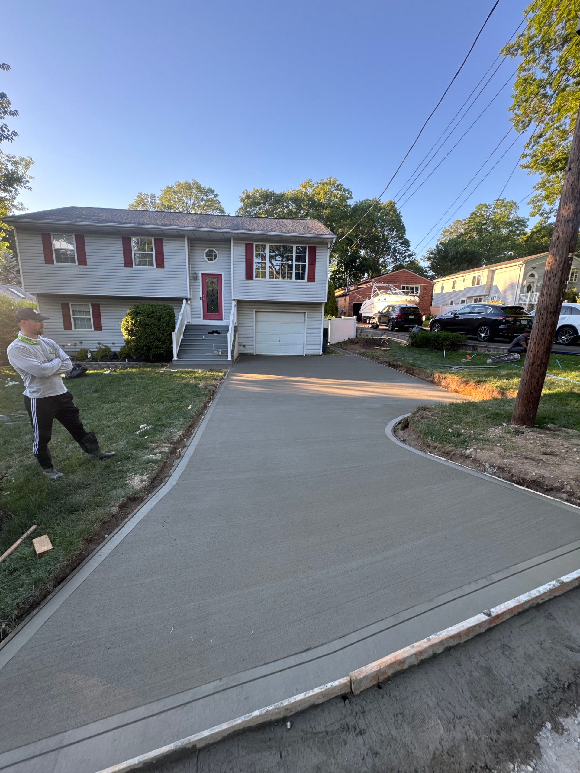 Driveway leading to a suburban split-level house at dusk, with a person standing on the lawn.