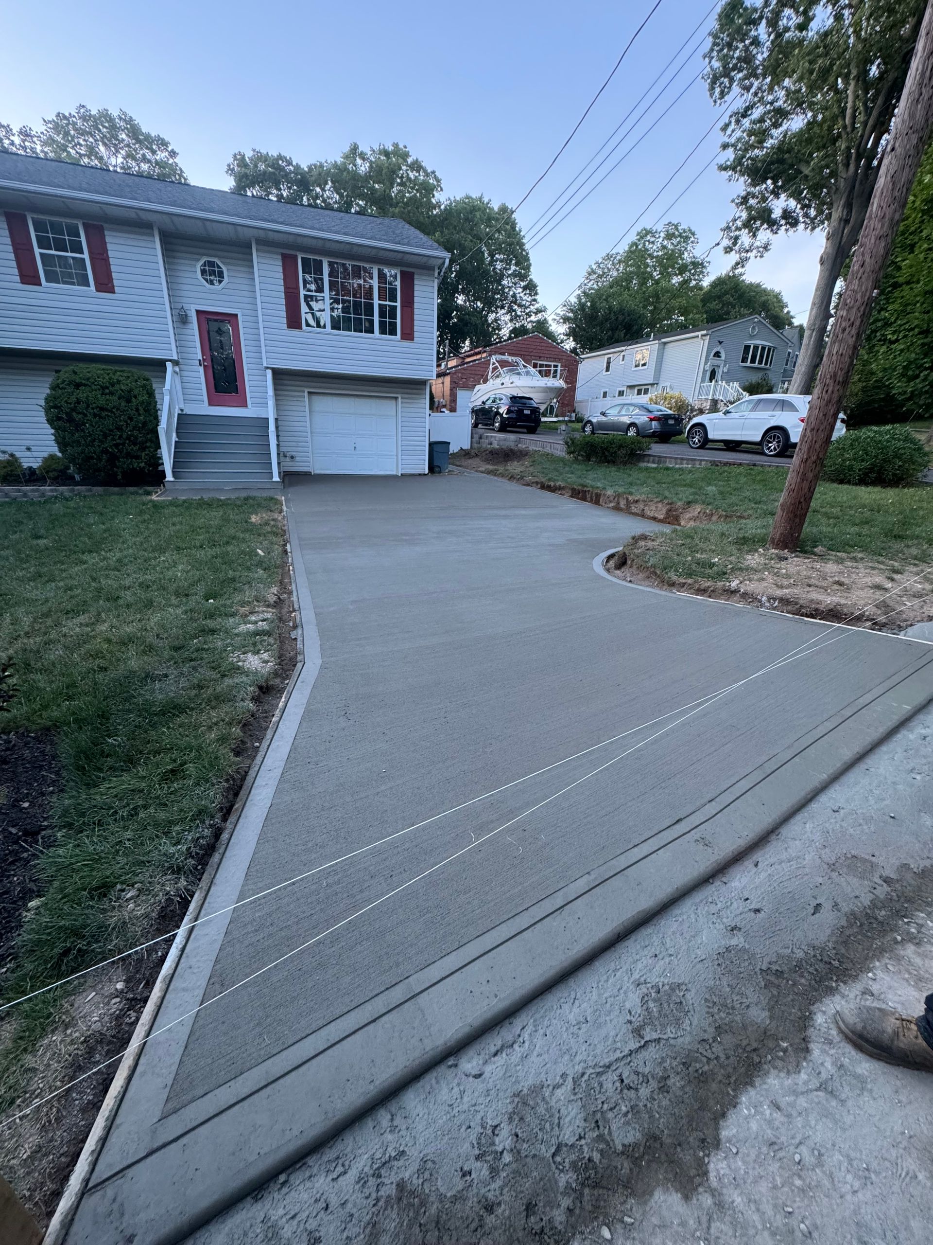 Suburban driveway sloping up to a two-story house with garage at dusk