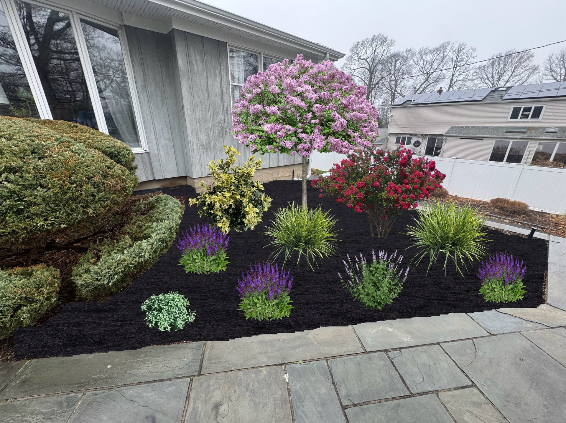 Front yard flower bed with pink flowering tree, red and purple blooms, and green shrubs beside a house