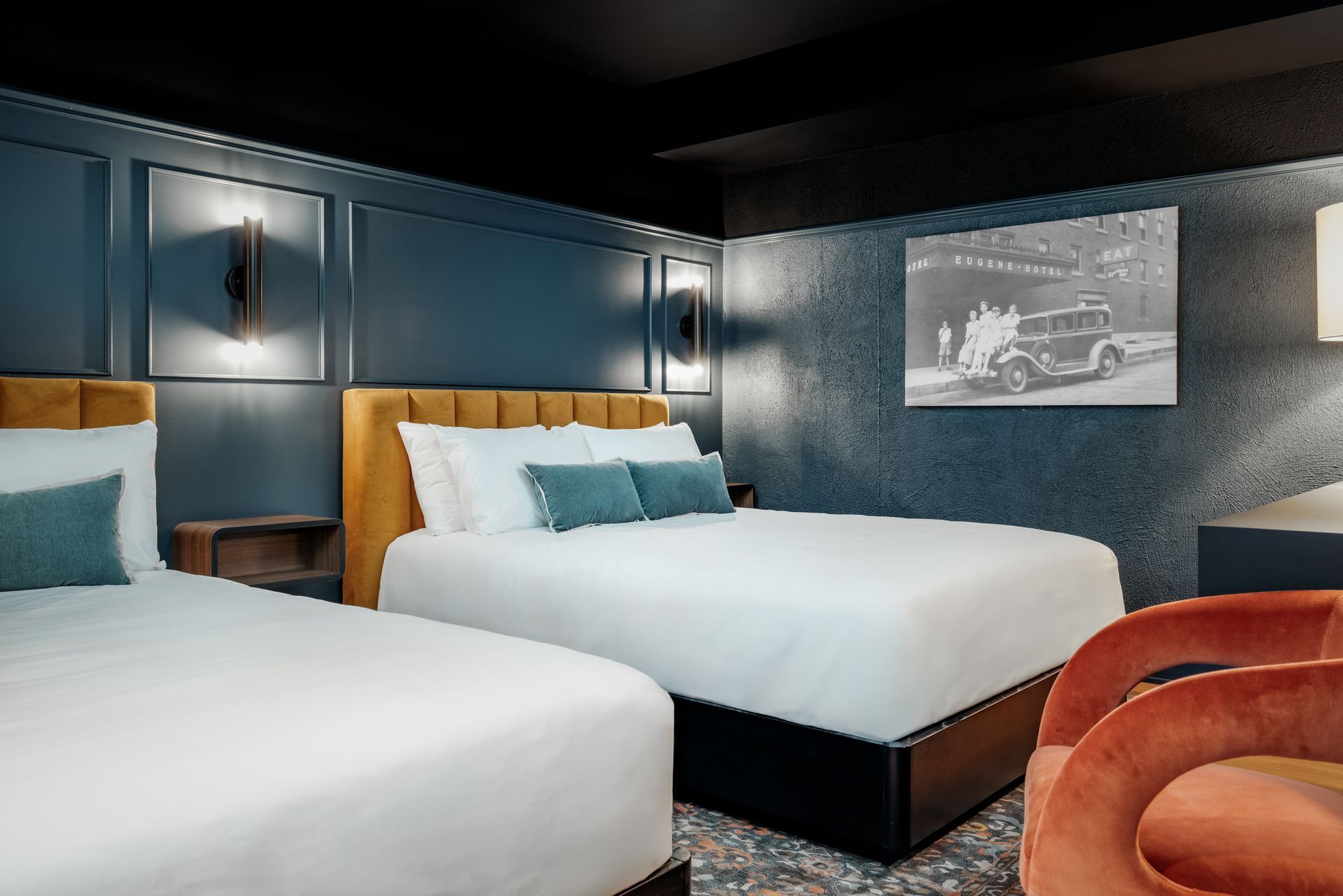 A modern bedroom featuring a brown paneled headboard, a floating wood nightstand with a small plant, and a white bed.