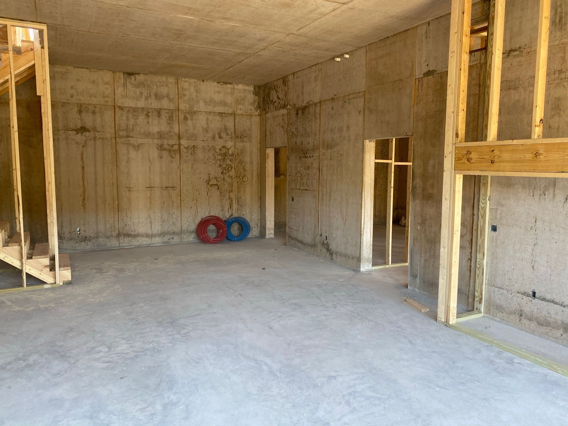 An empty room with concrete walls and a wooden staircase.