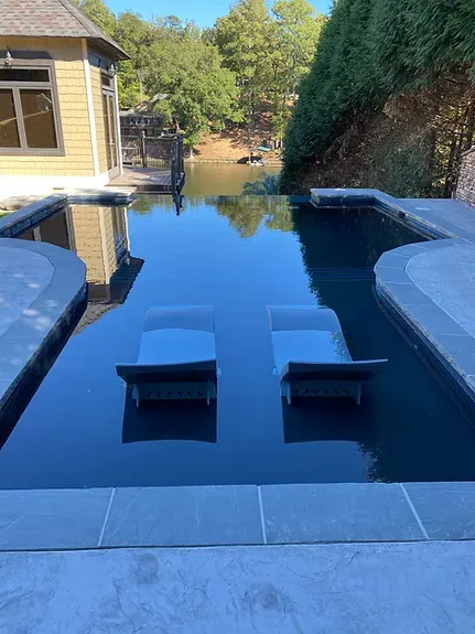 A large swimming pool with two lounge chairs in it.