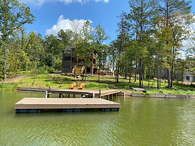 There is a dock in the middle of a lake with a house in the background.