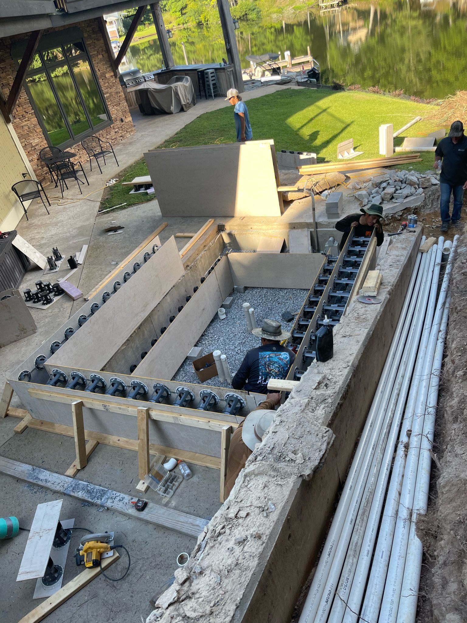 A group of people are working on a swimming pool under a bridge.