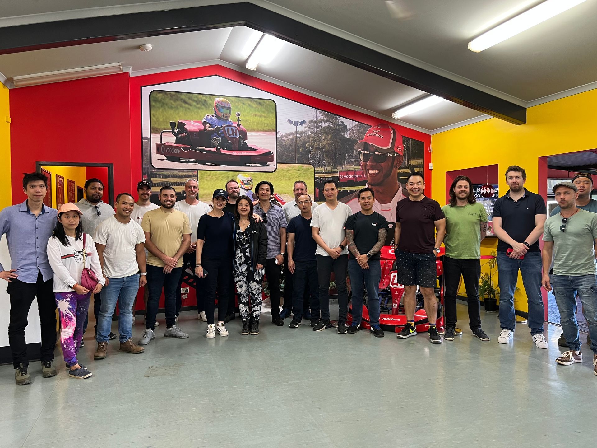 Group of people inside a red and yellow showroom with lawn care equipment, smiling for a photo.