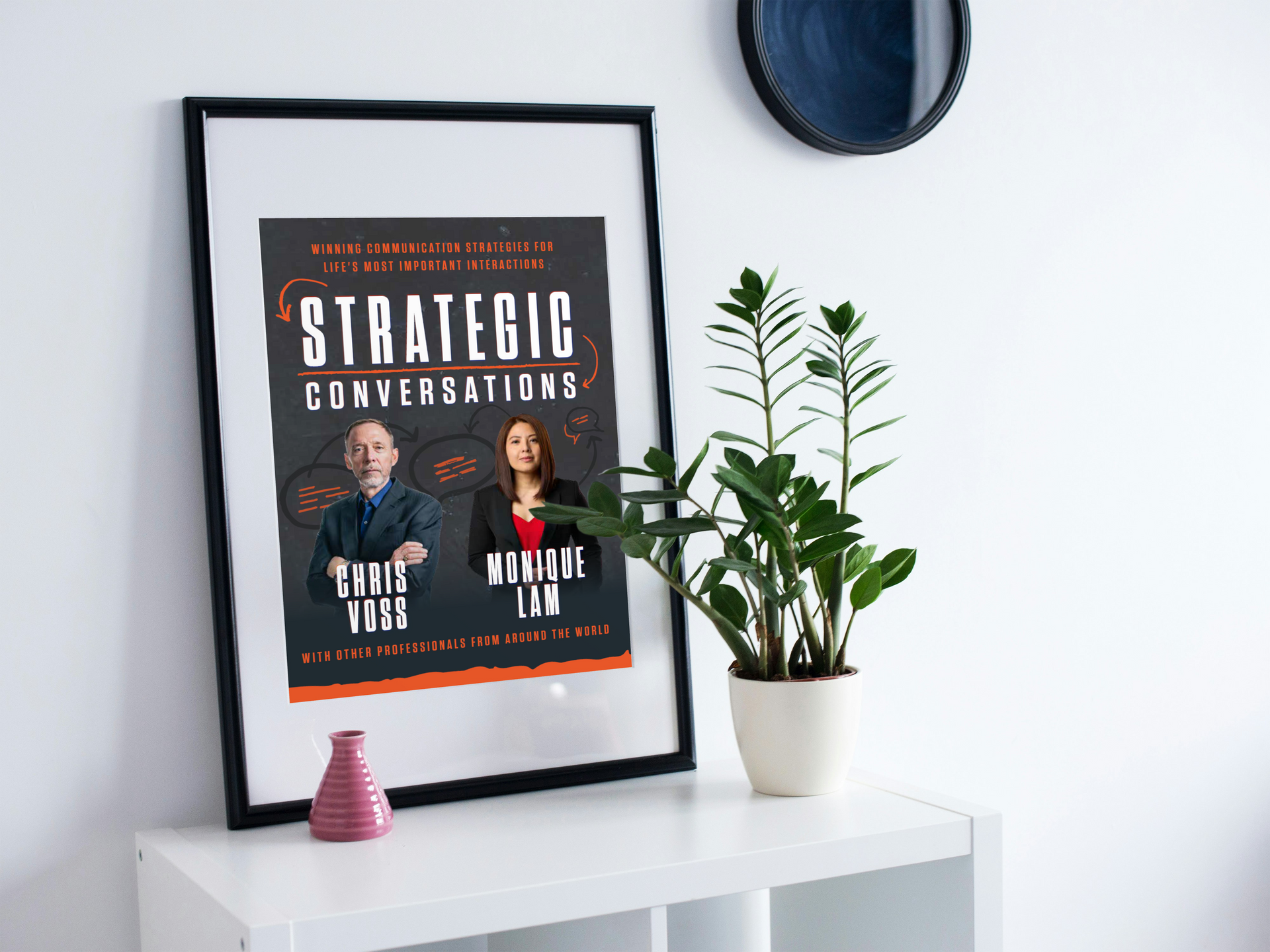 A framed poster is sitting on a table next to a potted plant.