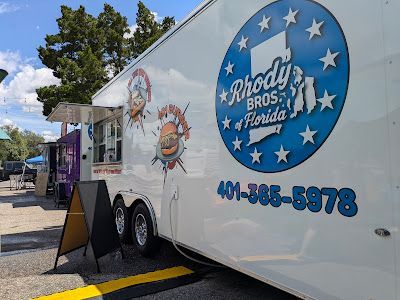 A white food truck is parked in a parking lot.