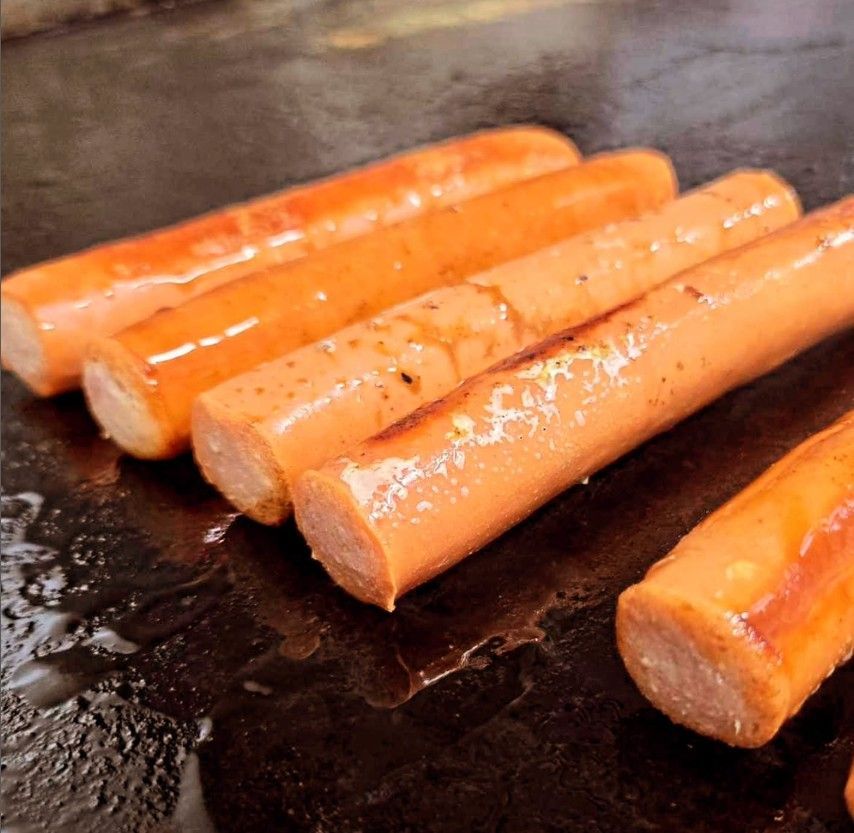 Wieners grilling on a grill.