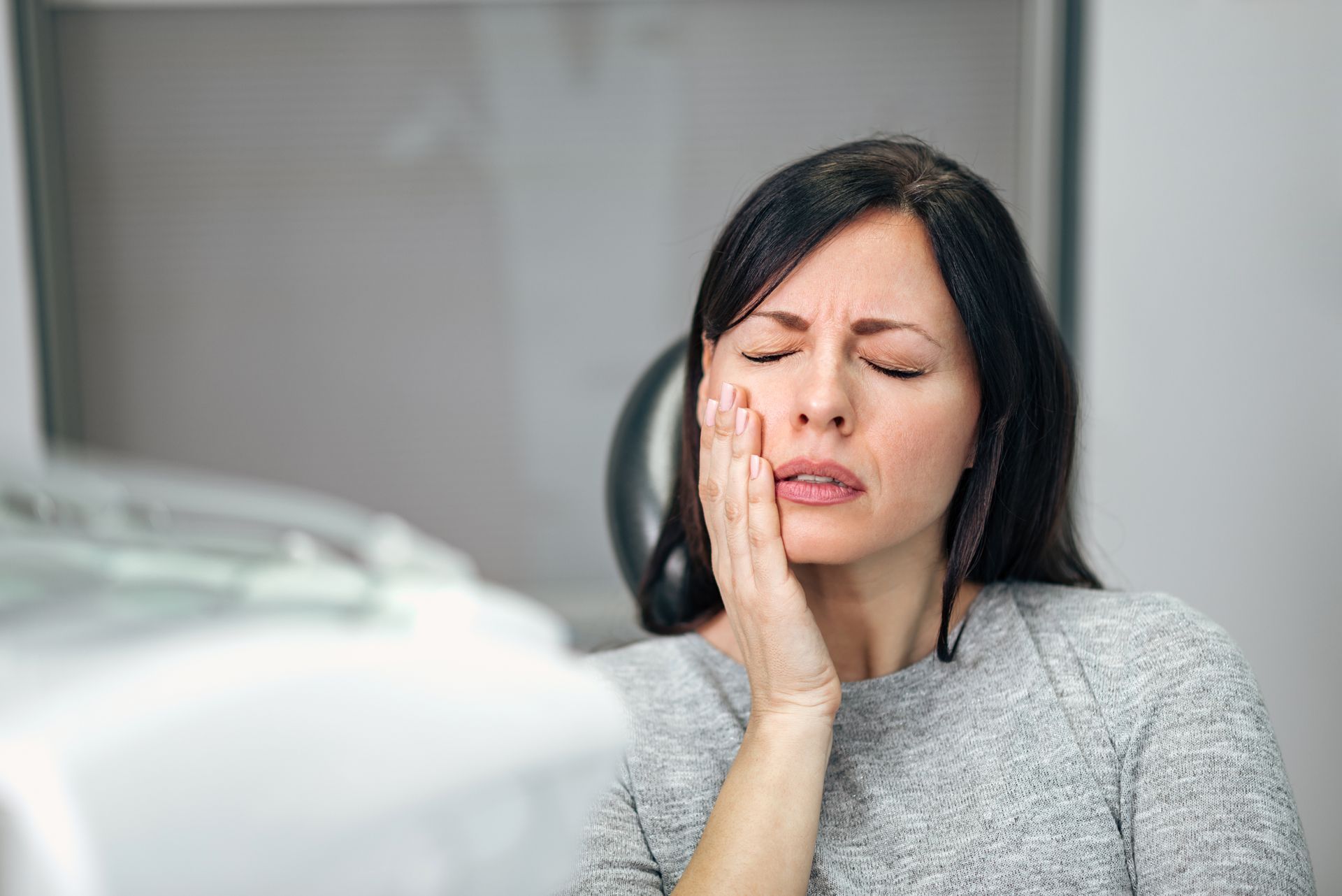 Portrait of a young woman with a toothache at an emergency dentist's office.