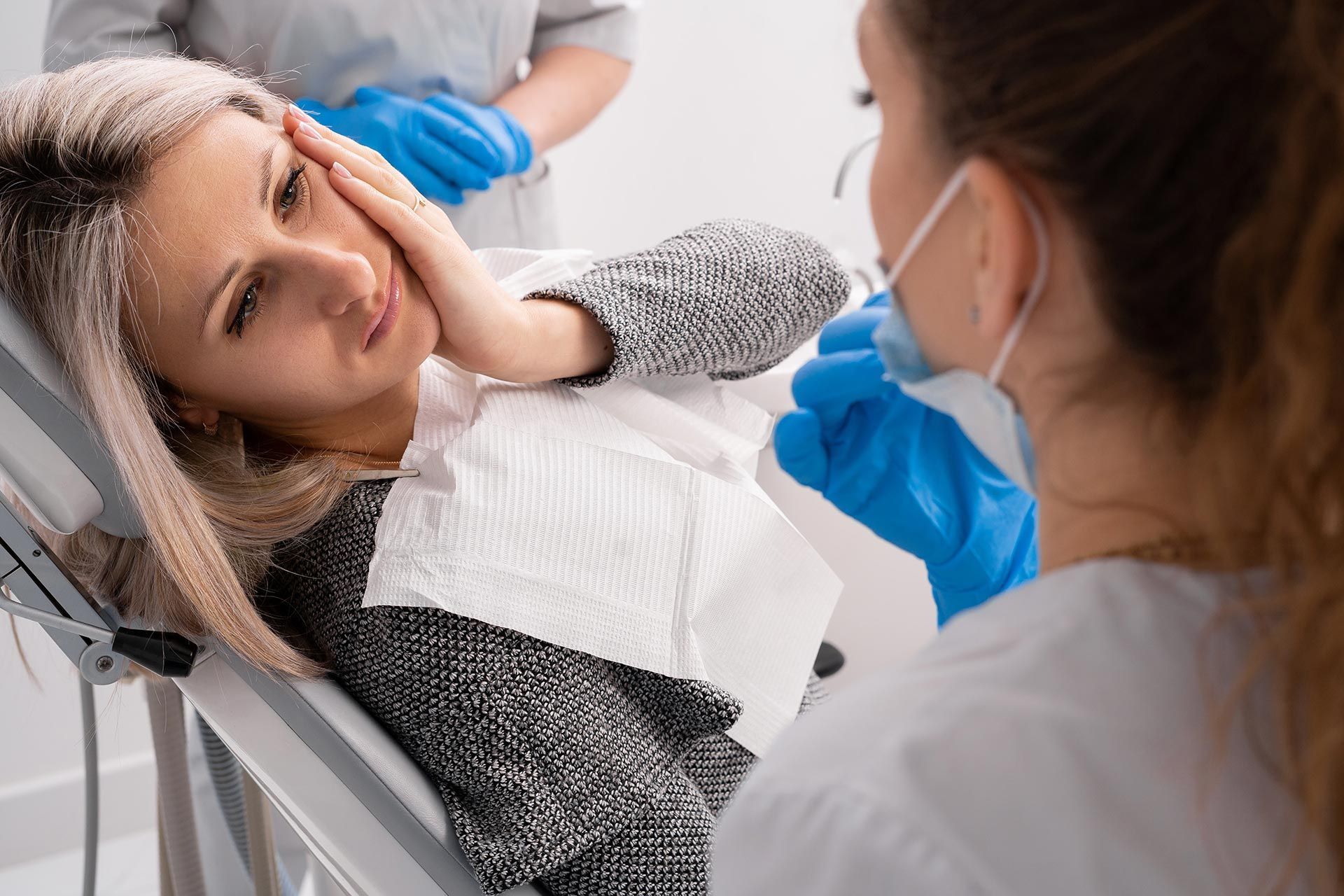 A woman with a severe toothache is at the dentist.