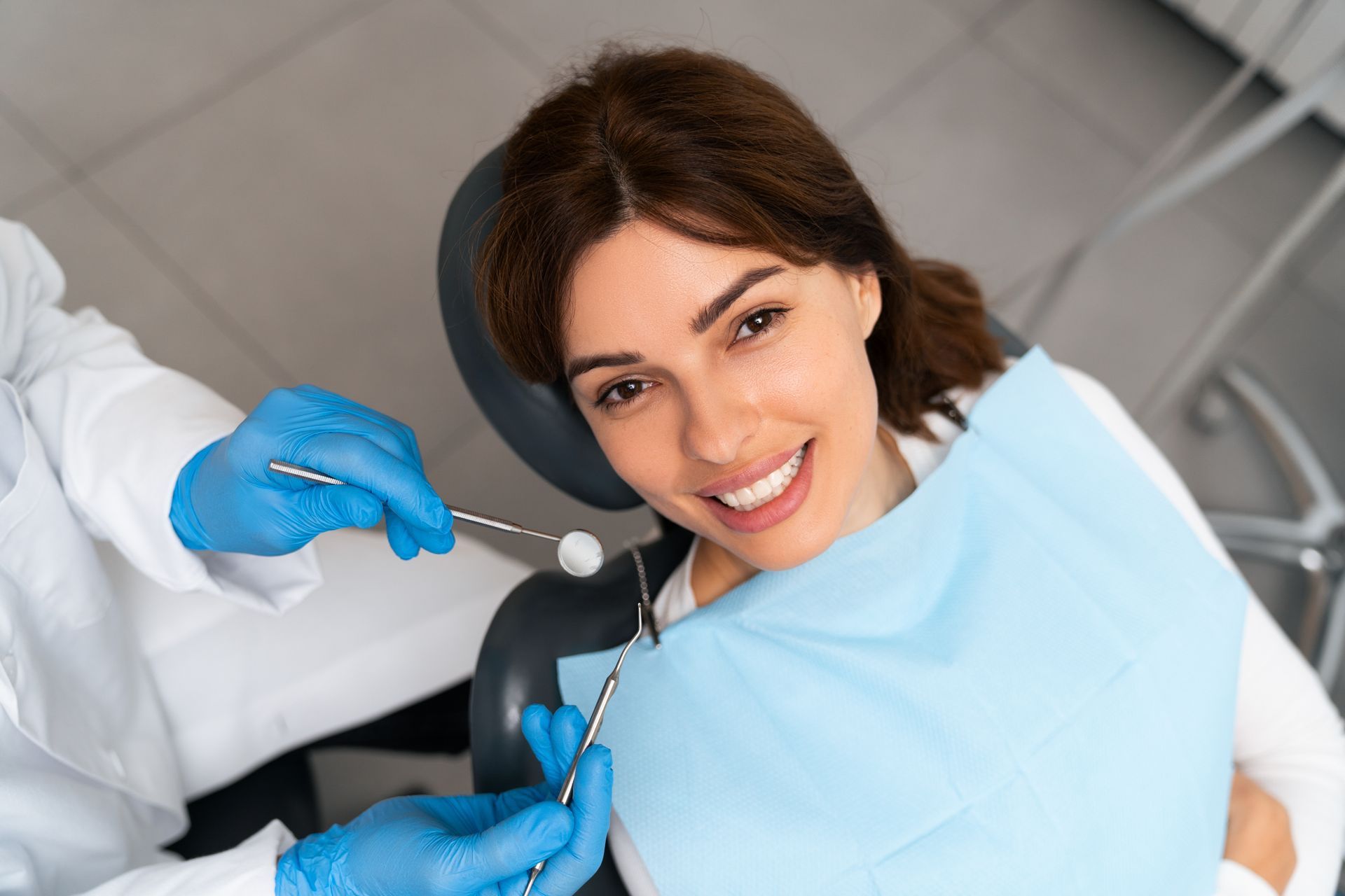 A general dentist performing a dental examination on a patient in a dental chair. A general dentist performing a dental examination on a patient in a dental chair.