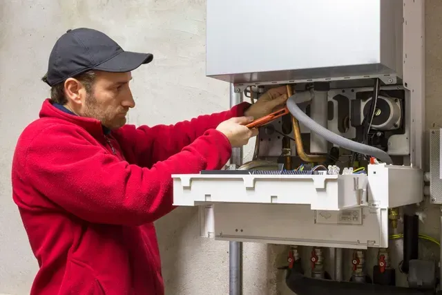 A man is working on a boiler in a basement.