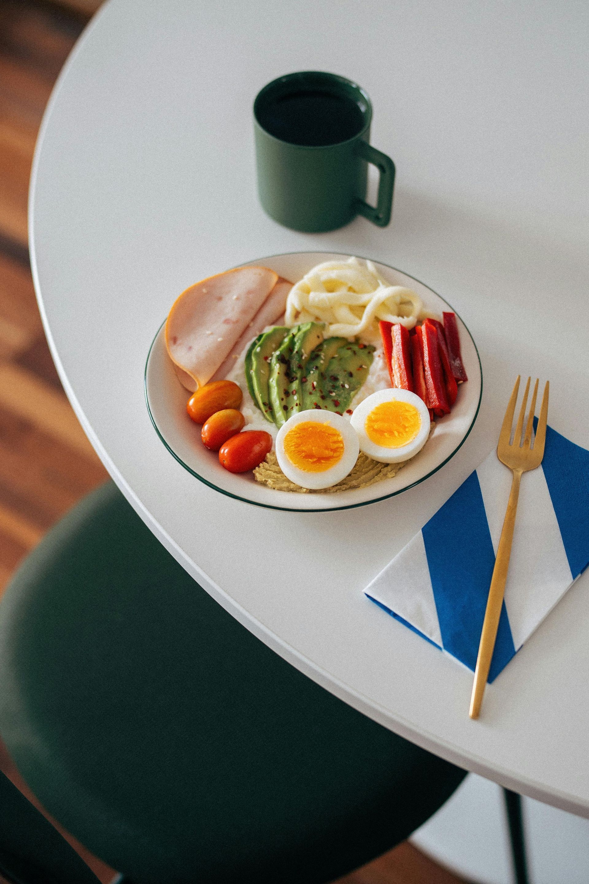 Een bord met eten op tafel, een vork en een kopje koffie.