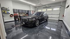 A home garage featuring a newly coated epoxy floor and a car parked within the space.